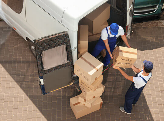 removal men load cardboard boxes into van