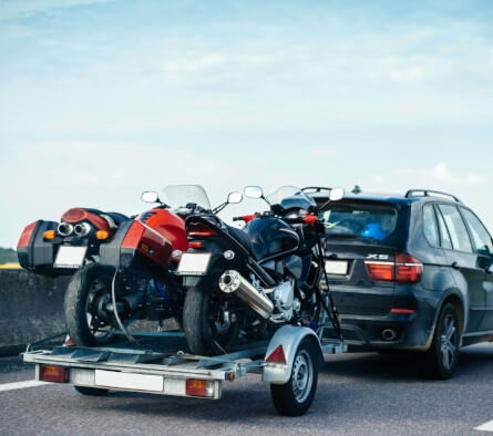 SUV towing a trailer loaded with two motorcycles on a highway